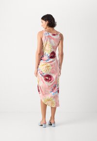 Luftig rosa midi-kjole med et fargerikt blomsterdesign, justerbare snørestropper og splitt i siden, kombinert med lyseblå høye sandaler.