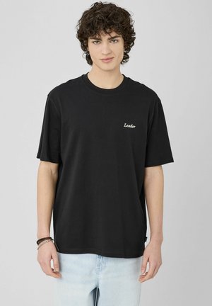 T-shirt en coton noir à manches courtes et col rond. Présente le logo "Leader" en blanc sur la poitrine gauche. Coupe décontractée.