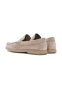 Beige suede loafers with a rounded toe, textured surface, minimal stitching detail, and a flat, flexible rubber sole.