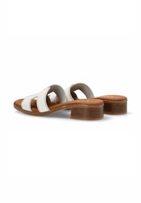 Sandalias de tacón blancas de cuero con diseño recortado, tacón de madera marrón y textura suave. Presentan un estilo cómodo de poner y quitar.