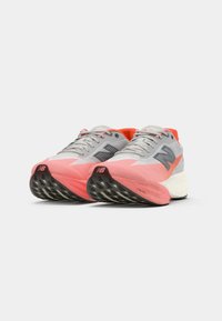 Chaussures de course légères avec un dessus gris, des accents roses et une semelle texturée noire. Elles disposent d'un talon rembourré et d'un tissu en mesh respirant.
