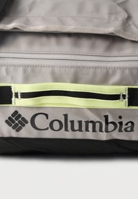 Γκρι και μαύρο τμήμα τσάντας Columbia με ανοιχτό κίτρινο ιμάντα και ορατή λεπτομέρεια φερμουάρ.