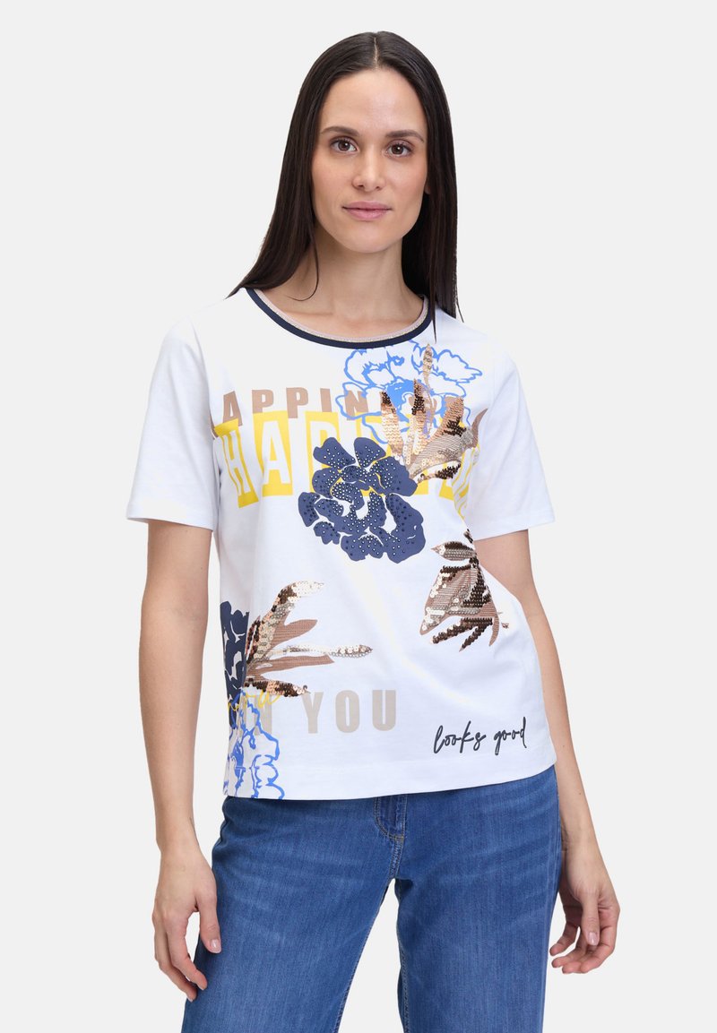 T-shirt en coton blanc avec des motifs floraux colorés en bleu, or et marine, avec des accents de texte "BONHEUR", "VOUS" et "ça à l'air bien."