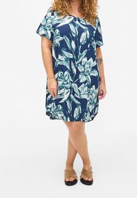 Kortärmad klänning i knälängd i marinblått med ett blommönster i teal och vitt. Tillverkad av mjukt tyg, med en avslappnad passform och rundad halsringning.