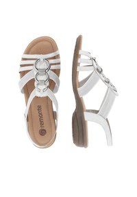 Sandales blanches à lanières avec des accents circulaires métalliques, dotées d'un petit talon et d'une semelle intérieure texturée marron, conçues pour le confort et la stabilité.