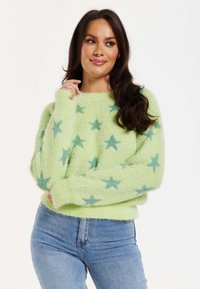 Fluffy, light green sweater with a crew neckline and long sleeves, featuring teal star patterns throughout. Soft texture and loose fit.