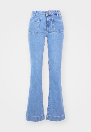 Lyseblå jeans med høj talje, forlommer med lap og vide ben mod en ensfarvet hvid baggrund.