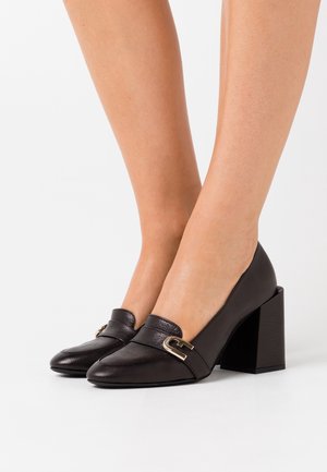 Zapatos negros de cuero con tacón cuadrado, con punta redondeada y un acento decorativo de hebilla dorada. Acabado texturizado en la parte superior.