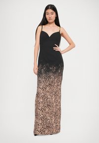 Robe noire avec un corsage ajusté et un bas en imprimé léopard, dotée de fines bretelles et d'un accent décoratif en or. Texture lisse.