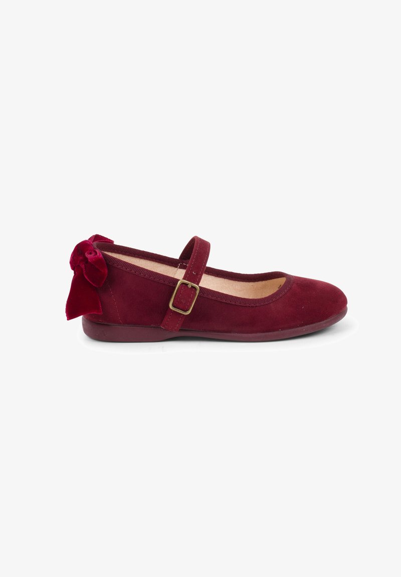 Burgundy suede ballet flats with a round toe, flat sole, and a decorative velvet bow at the heel. Features an adjustable strap with a buckle.