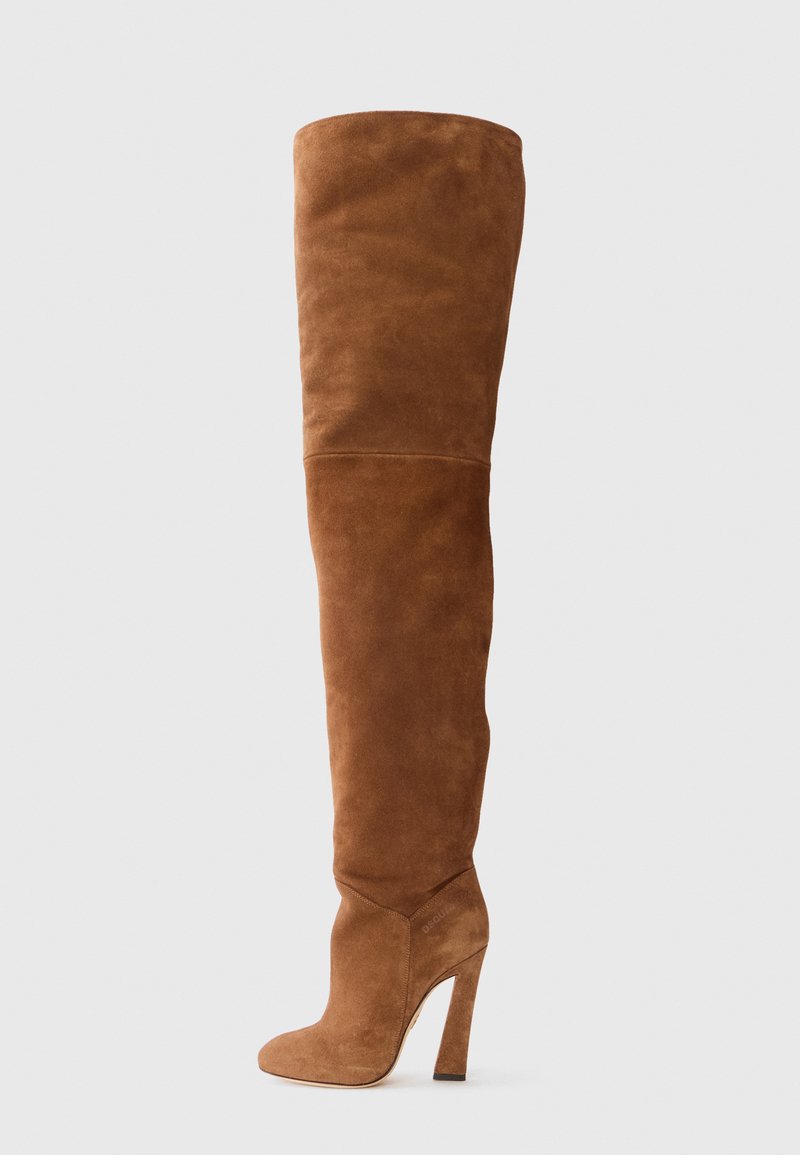 Bota alta de ante marrón, hasta el muslo, con punta afilada, tacón de aguja y textura suave; presenta un diseño sin costuras y una silueta ajustada.