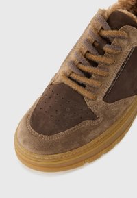 Baskets en suede marron avec un embout perforé, des accents en cuir noir contrastants et une semelle en caoutchouc beige. Dotées de lacets plats et d'un col rembourré.