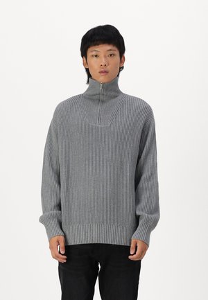 Maglione grigio a coste con colletto alto e chiusura a metà cerniera. Presenta maniche lunghe e una vestibilità leggermente comoda. Materiale in maglia testurizzata.