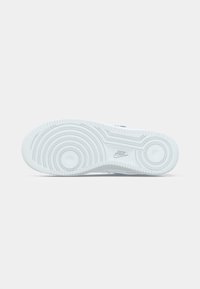 Såle av en hvit Nike-sko med sirkulære mønster og Nike-logoen preget nær buen.