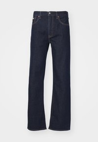 Tumed sinine denim sirge jala teksad, millel on tõmblukk, nööbikinnitusega ja kontrastsete õmblustega. Omab kahte eesmist taskut ja klassikalist disaini.