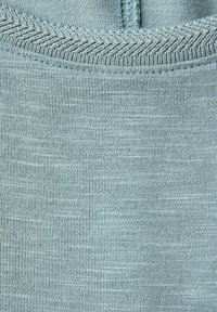 Jasnoniebieska tkanina o gładkiej teksturze, z pionowymi prążkami i kontrastowym ściegiem w kształcie chevronu wzdłuż górnej krawędzi.