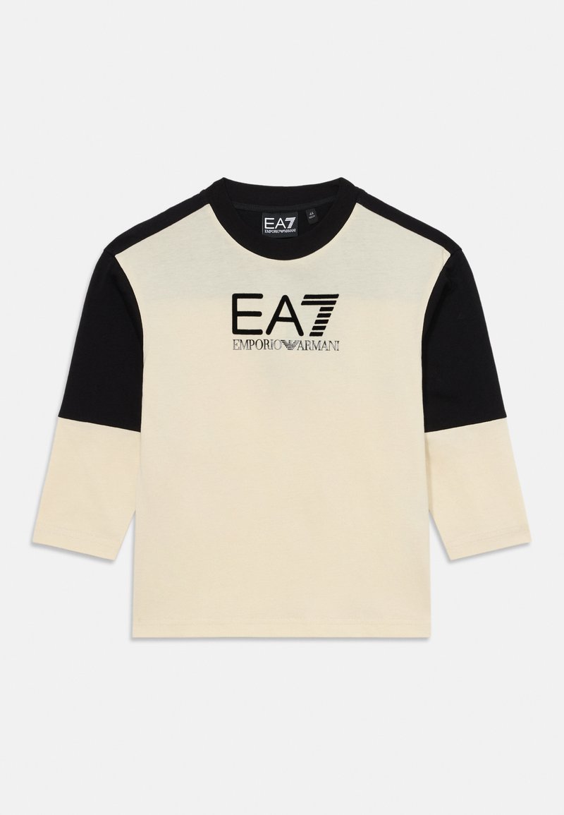 T-shirt à manches longues crème et noire avec un col rond. Présente le logo 'EA7 Emporio Armani' en noir. Fabriqué en tissu de coton doux.