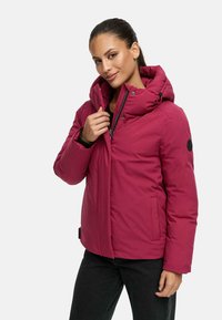 Roze gewatteerde jas met een hoge kraag, ritsluiting, zijzakken en een logopatch op de mouw. Geschikt voor koud weer.