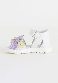 Sandalo bianco con decorazioni floreali in viola, rosa e giallo. Caratterizzato da cinturino regolabile, design aperto e suola testurizzata.