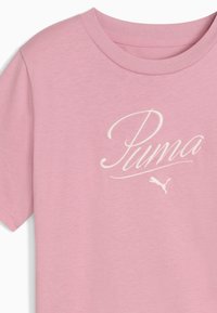 T-shirt rose clair à manches courtes avec un logo "Puma" brodé en blanc et un petit graphique de puma blanc près du logo.