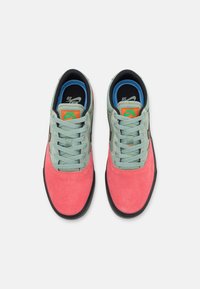 Baskets Nike avec une tige en daim rose et des accents en cuir vert menthe, doublure intérieure noire et bleue, et lacets plats.