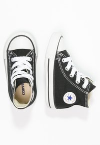 Svarte lerret høye sneakers med hvite gummisåler, hvite snører og en blå stjerne-logo på siden. Side-søm detalj synlig.