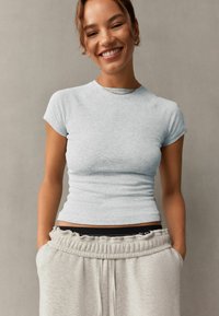 Lys grå ribbet kortærmet top med en tætsiddende design, parret med lys grå sweatpants med elastisk talje og sidelommer.