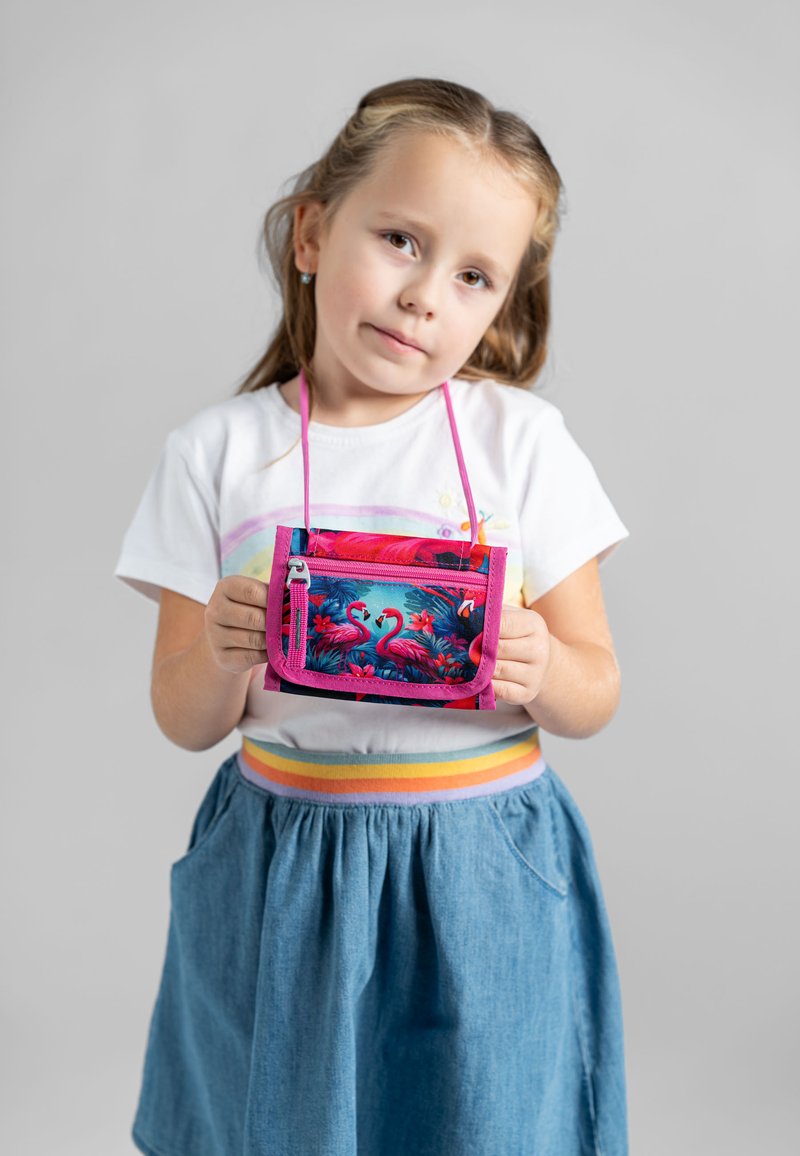 Pochette a tracolla colorata con design di fenicottero, dettagli in rosa e chiusura con zip, tenuta da un bambino in una gonna di jeans.