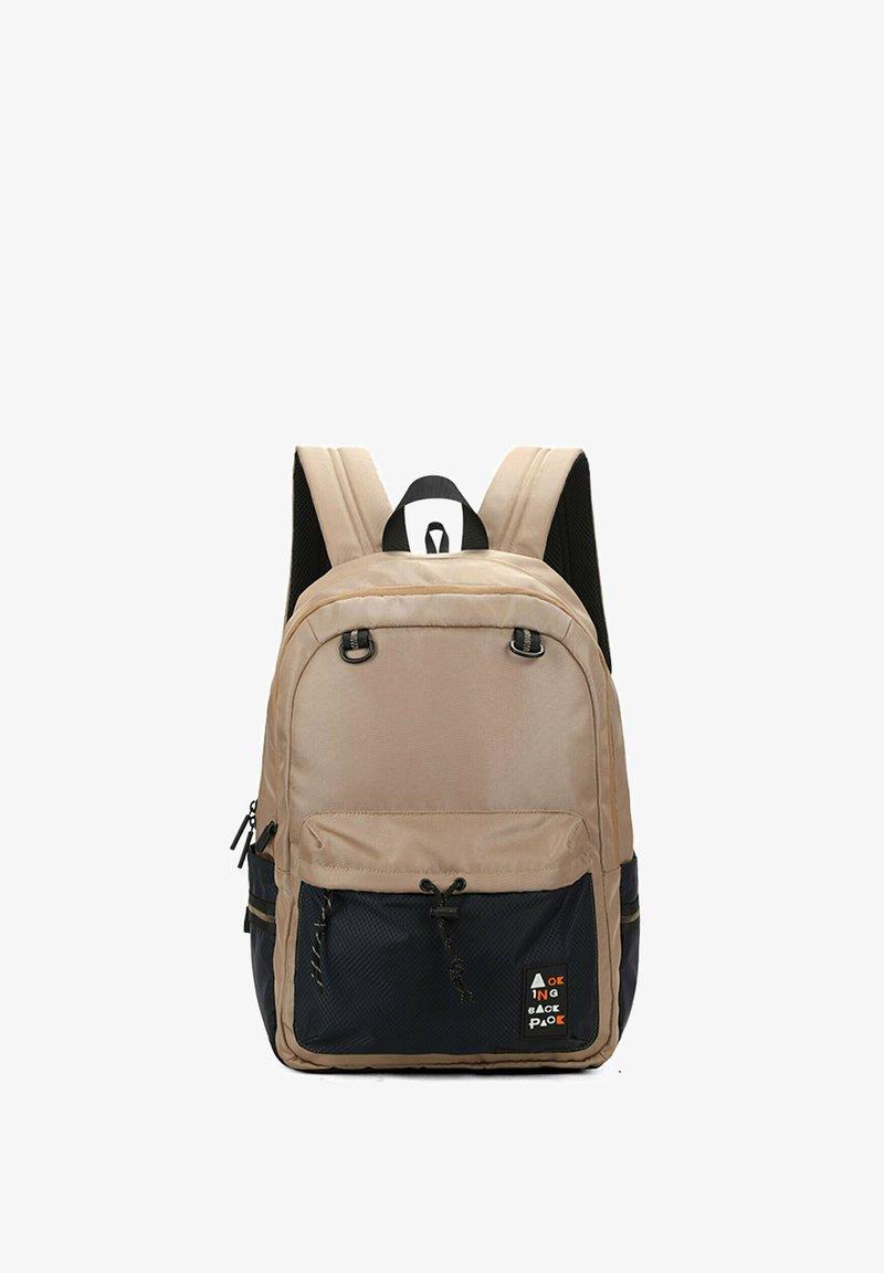 Sac à dos tan avec des bretelles en mesh noir, deux compartiments zippés, une poche avant en tissu noir texturé et un accent de logo. Design légèrement rembourré.