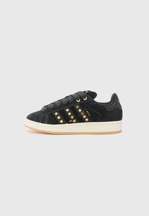 Sort ruskind lav-sneakers med guldbelagte striber, sorte snørebånd, hvid sål og teksten "CAMPUS" på siden.