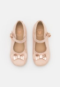 Scarpine da balletto rosa chiaro con tomaia in rete testurizzata, punta rotonda e un accento a fiocco metallico. Presentano una fascia con fibbia laterale.