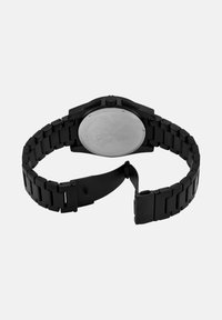 Črno metalno uro z mat površino; ima povezano zapestnico in okroglo ohišje s gladko, odbojno površino na hrbtni strani ter krono.