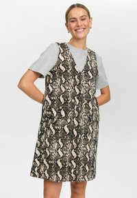 Mouwloze jurk met een V-hals, voorzien van een zwart-beige slangenprintpatroon. Gemaakt van gestructureerde stof en heeft twee voorzakken.