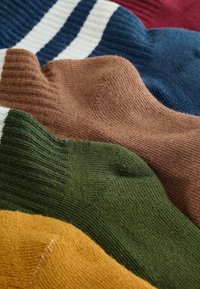 Cuatro pares de calcetines de diferentes colores: azul oscuro, marrón, verde y mostaza, con una textura acanalada y material de punto suave.