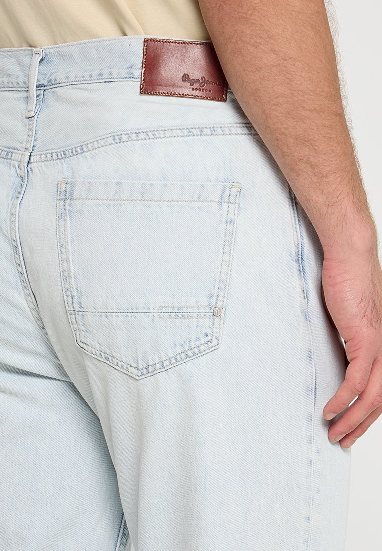 Helle blaue Jeans aus Denim mit geradem Schnitt, versehen mit einem Leder-Patch am Rücken, einer einzelnen Gesäßtasche und minimaler Verblassung.