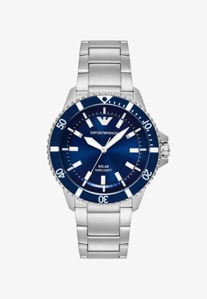 Reloj de acero inoxidable con esfera azul, manecillas y marcadores en tono plateado. Cuenta con energía solar, bisel unidireccional y resistencia al agua de 100 m.