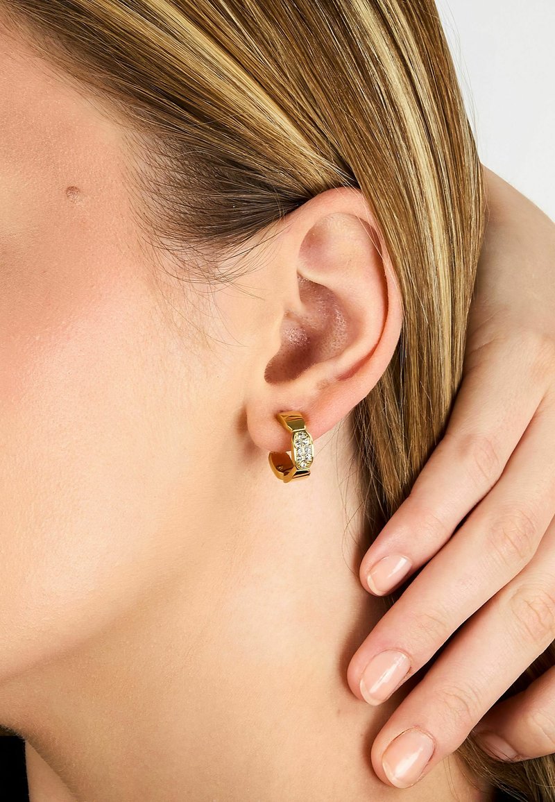 Boucles d'oreilles créoles en or avec une tige rectangulaire, ornées de cristaux clairs au centre. Surface lisse, finition brillante et design moderne.