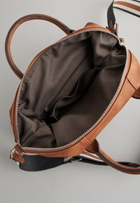 Braune Ledertasche mit Reißverschluss, ausgestattet mit einem dunkel gefärbten Innenraum, mehreren Fächern und einem kontrastierenden Schulterriemen mit Streifen.