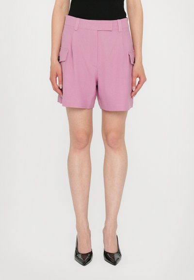 Shorts lila cu un design croit, dotate cu buzunare laterale și o textură netedă, asortate cu tocuri lăcuite negre.