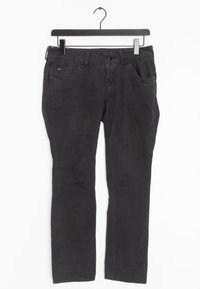 Pantaloni in denim neri esposti su un appendiabiti. Presentano un taglio dritto, cinque tasche e una texture sottile con un'usura minima.