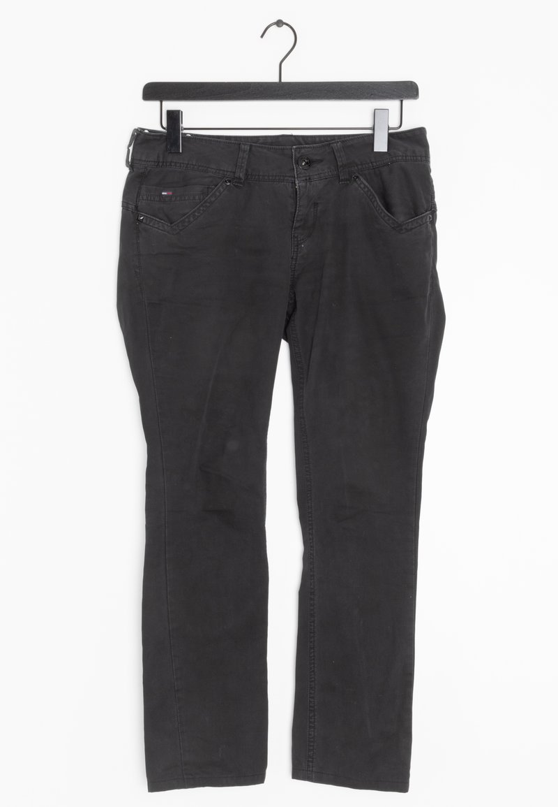 Pantaloni in denim neri esposti su un appendiabiti. Presentano un taglio dritto, cinque tasche e una texture sottile con un'usura minima.