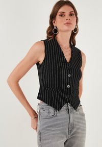 Čierna pruhovaná vesta s výstrihom do V, piatimi prednými gombíkmi a dvoma prednými vreckami, skombinovaná so svetlo sivými nohavicami s vysokým pásom.