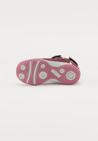 Suola di scarpa viola con accenti grigi, caratterizzata da una suola rosa testurizzata con grip rotondi e due scanalature orizzontali per migliorare la trazione.