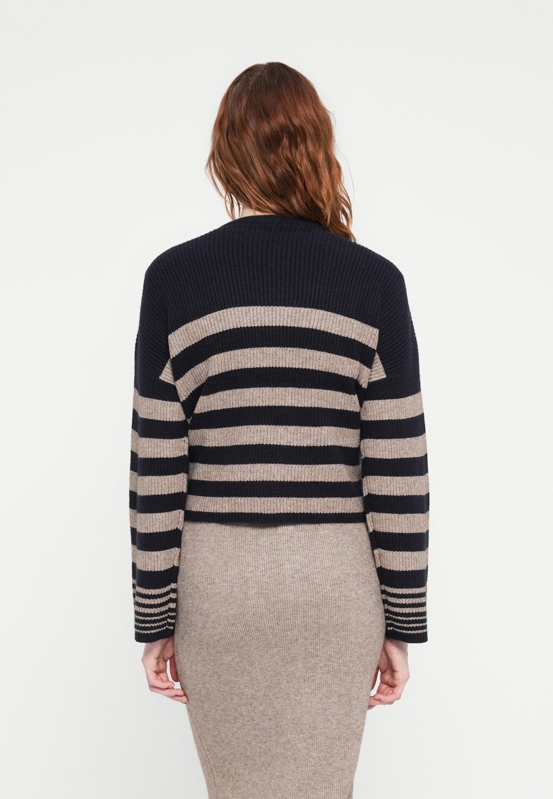 Marineblau und beige gestreifter Strickcardigan mit cropped Design und langen Ärmeln. Texturiertes Material mit gerippten Akzenten an Schultern und Bündchen.