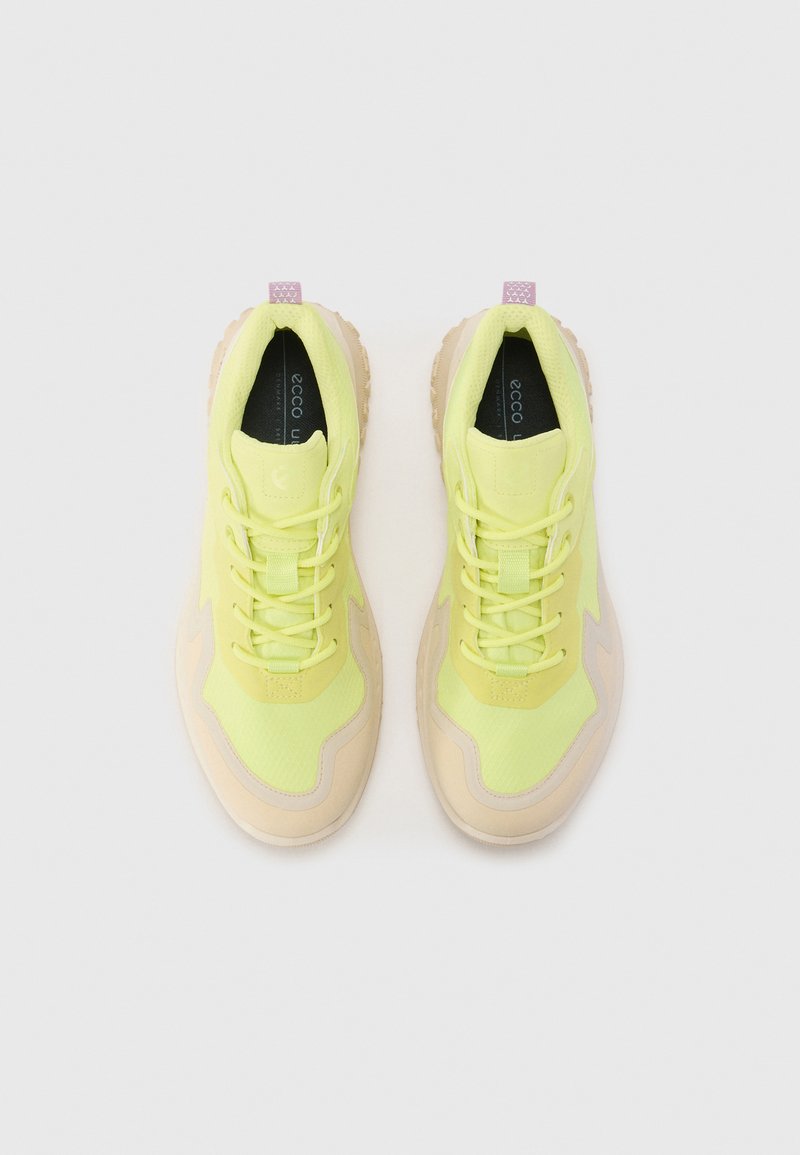 Jasnozielone buty sportowe z siateczkową cholewką, beżowymi akcentami i teksturowaną gumową podeszwą. Posiadają tradycyjne sznurowanie oraz pętlę na pięcie.
