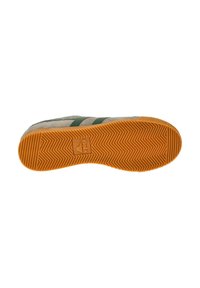 Zapatilla con parte superior de ante beige, rayas verdes y suela de goma naranja texturizada con patrón de espiga.