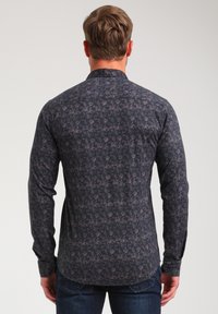 Camicia a maniche lunghe con motivo scuro e colletto. Presenta un design floreale dai colori chiari su uno sfondo scuro. Polsini con bottoni.