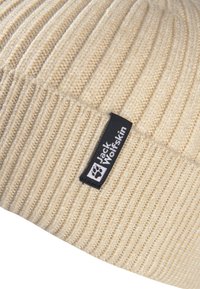 Beanie a coste beige con un'etichetta nera del logo Jack Wolfskin cucita sul polsino.