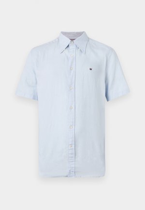 Camisa de botón de manga corta azul claro, hecha de una tela suave, con un cuello clásico y un pequeño logo en el pecho.