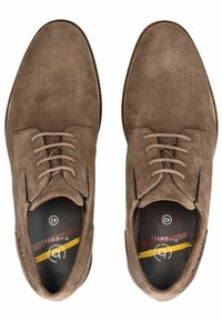 Zapatos de ante marrón con textura perforada, puntera redonda y diseño de cordones de cinco ojales. Presentan una plantilla impresa con el logo de la marca y rayas de colores.